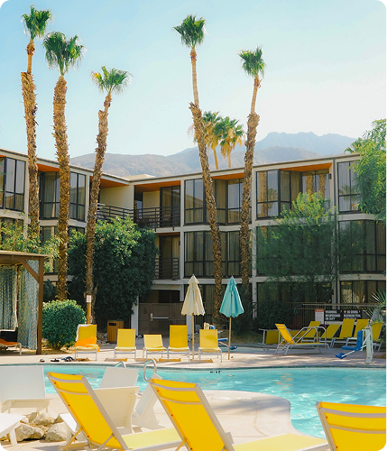 a pool with palm trees and a building with a mountain in the background